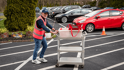 Elan volunteer running meals out to waiting drivers.