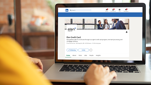 A laptop shows the screen of the Elan Credit Card LinkedIn page.